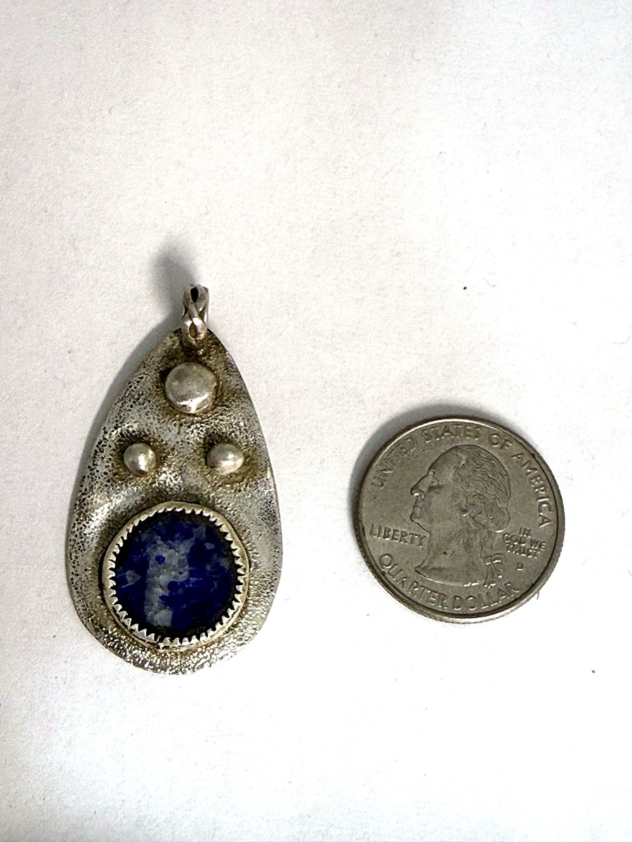 Sterling silver teardrop pendant with a lapis lazuli cabochon on hand-textured reticulated silver.