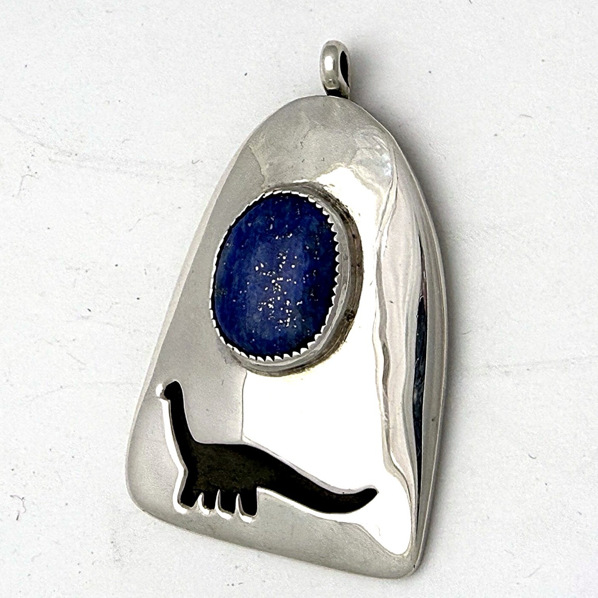 Sterling silver sauropod-silhouette pendant with a lapis lazuli cabochon.