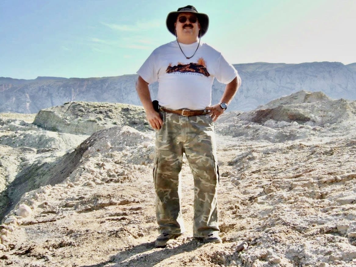 Bosco standing in eroded badlands terrain during field work
